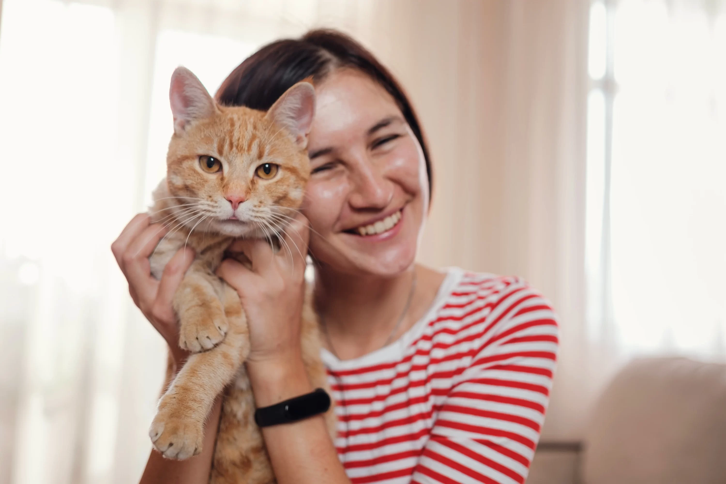 woman smiling holding cat. cat day.pets24