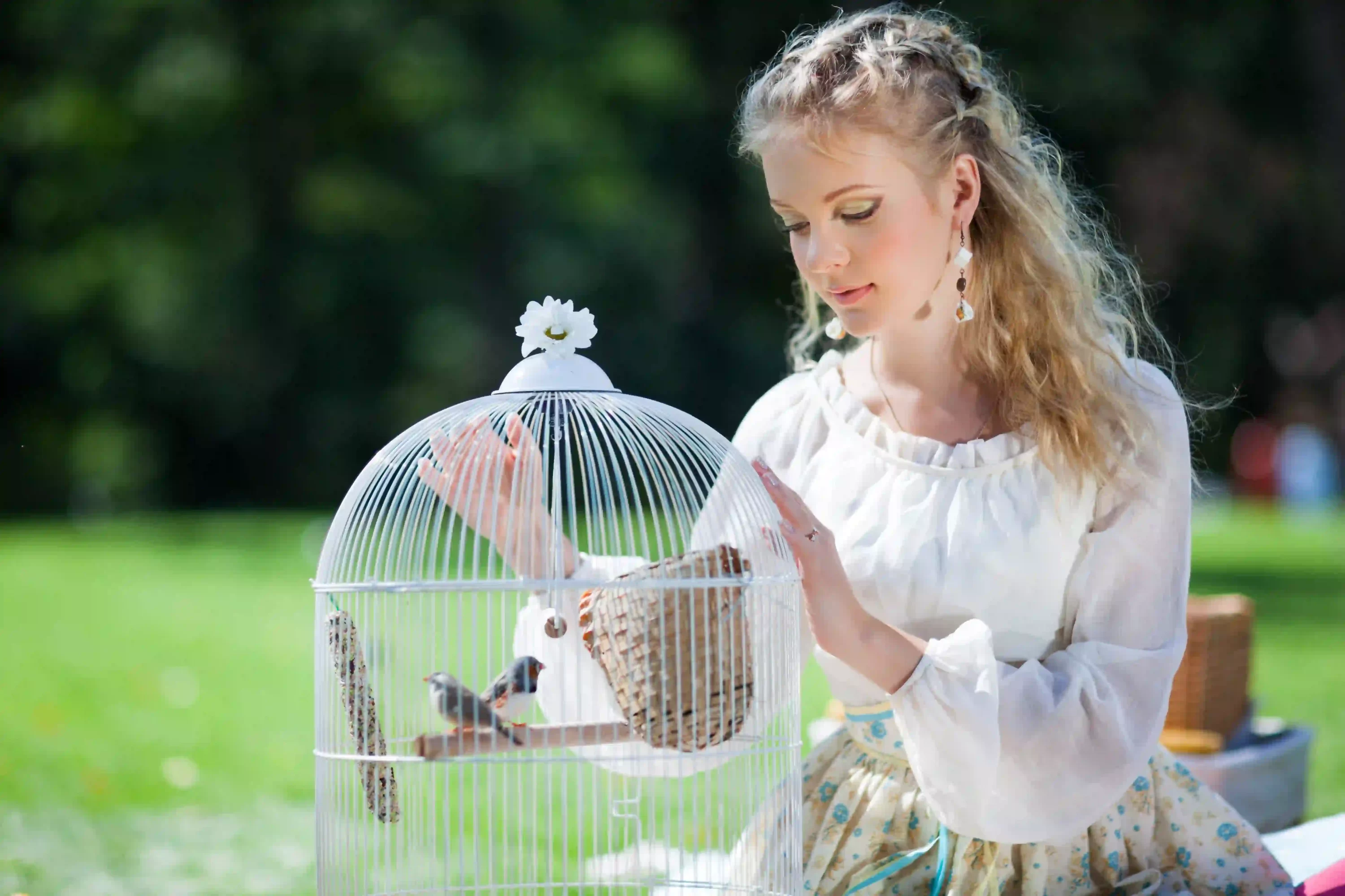 Woman looking at bird in a cage. Amazing benefits of owning pet birds